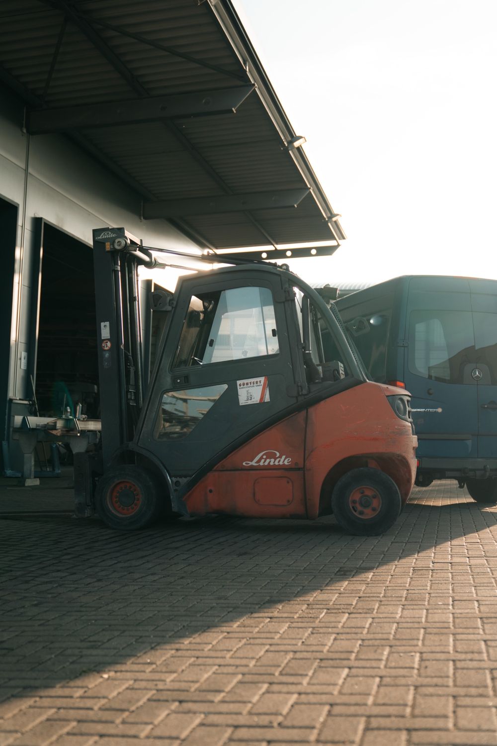 Gabelstapler vor der Werkhalle eines Metallbaubetriebs im Gegenlicht